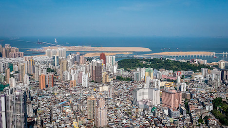 マカオ半島の中央から北西を望む空撮画像。奥に見えるのが香港と広東省珠海市、マカオの3地を結ぶ海上橋「港珠澳大橋」と出入境施設の建設予定地となる人工島＝2015年4月（写真：GCS）