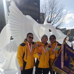 優勝旗を手に作品の前で記念撮影に臨むマカオ代表チームの3人=2月9日、北海道札幌市(写真:MGTO)