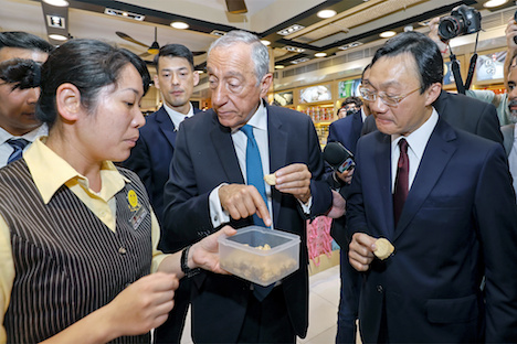 マカオ歴史市街地区周辺の視察中にマカオ銘菓の杏仁餅を試食するポルトガルのソウザ大統領（中央）＝2019年5月1日、マカオ（写真：GCS）